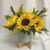 Sunflower arrangement in a pale blue vase on a wooden stand