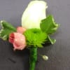 Boutonniere with a white rose, pink rosebud, and green accent flower