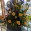 Pale yellow roses take center stage in this tall, layered funeral urn