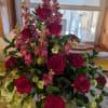 A lush, formal funeral spray that reads with quiet romance-deep red roses