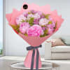 Pink bouquet of peonies wrapped in pink paper with a dark ribbon