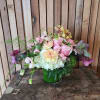 A low, garden-style arrangement in soft seasonal tones of white, pink, and