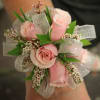 Pink rose corsage with silver ribbon and small white filler flowers