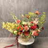 Large mixed flower arrangement in a gold vase on a white stand