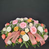 Large pink, white, and peach rose arrangement with ribbons on a dark background