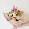 Hand-tied bouquet of pink and white roses wrapped in beige paper