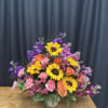 Mixed bouquet with sunflowers, orange roses, and pink carnations in a white vase