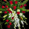 A lavish cascade of red roses, white lilies, and trailing white orchid