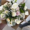 Hand-tied bouquet of white and blush flowers wrapped in brown paper