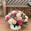 Pink and cream floral arrangement in a white round box