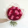 A dense, dome-shaped hand-tied bouquet of saturated red and soft pink roses