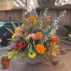 A ceramic pot filled with in season fall blooms that include maple