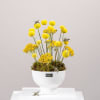 Yellow pom-pom flowers in a white pedestal vase with bee decorations