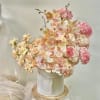 Peach orchids and pink hydrangeas arranged in a white hatbox
