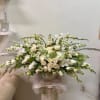 Large white floral arrangement with roses and orchids in a pedestal vase