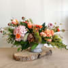 Low floral arrangement in a metal urn with peach and pink blooms