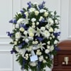 A formal oval standing tribute layered with white roses, lilies, chrysanthemums and