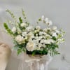 White floral arrangement with orchids and roses in a low container