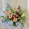 Tall mixed bouquet of pink roses and blue flowers in a glass vase