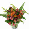 Mixed pink, orange, and burgundy flowers in a clear glass vase