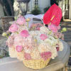 A delicate basket arrangement filled with soft pink and creamy white flowers