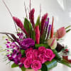 Pink roses and purple orchids arranged in a low vase
