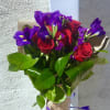 Bouquet of red roses and purple irises wrapped in brown paper