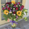 Bouquet of red roses and yellow sunflowers in a glass vase