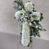 A standing cross arrangement with white and blue flowers cascade down the