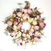 Dried floral wreath with pink and cream blooms on a white background