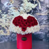 Heart-shaped red and white rose arrangement in a red cylindrical box