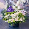 Bouquet of white and blush roses with purple orchids in a black box
