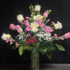 Soft blush and vivid pink roses reach upward in a tall clear