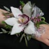 White orchid wrist corsage with silver ribbon on a wrist