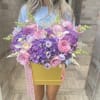 Large pink and purple flower arrangement in a gold box