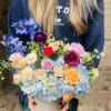 Mixed bouquet in a white vase with blue hydrangeas and roses