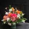 Bright pink and orange roses mingle with crisp white lilies in a