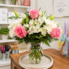 A soft and romantic arrangement featuring pink roses, white chrysanthemums, and delicate