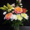 Peach-and-pink roses paired with pale yellow lilies give this flower arrangement a