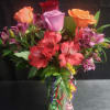 A bright, celebratory bouquet built around red, pink and orange roses with