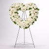 Heart-shaped white floral wreath on a black stand