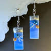 A pair of sky-blue stained glass dangle earrings that catch the light