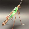 A whimsical copper-wire insect sculpture shaped like a light green praying mantis