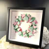 Soft pastel pink and mint-green glass pieces curve into a delicate wreath
