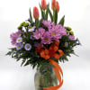 Spring Sunrise features vibrant sunset tulips rising above soft lavender chrysanthemums, bright