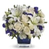 White lilies and roses arranged in a blue glass vase