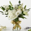 White floral bouquet in a clear glass vase with a gold ribbon