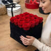A tight grid of sixteen premium red roses set against matte black