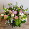 Pastel arrangement of roses, tulips, hydrangea and mixed blooms in a low glass vase