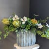 Arrangement of white flowers and green succulents in a striped ceramic pot